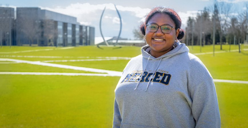 Isabella Mitchell poses for a photo with the Beginnings sculpture in the background.