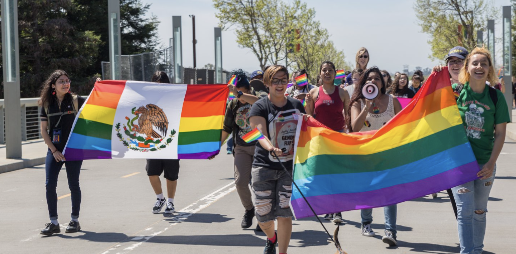 UCM students walking on scholars bridge holding pride flags